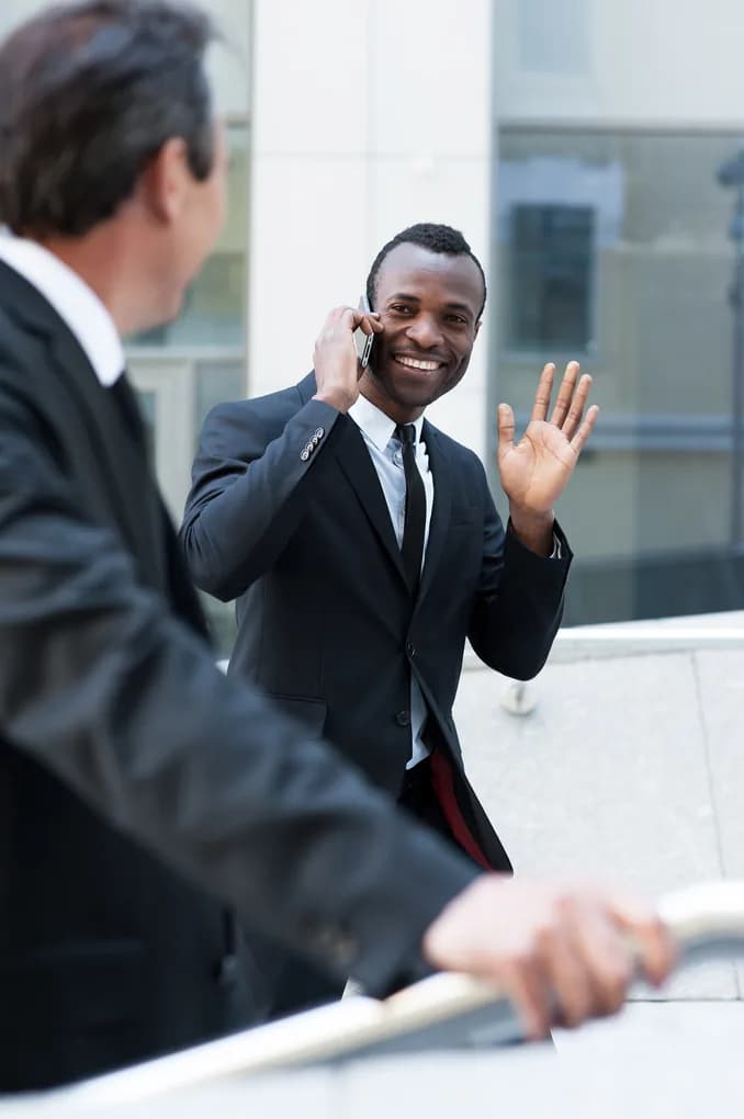 A greeter waving to a colleague while taking a call on the stairs