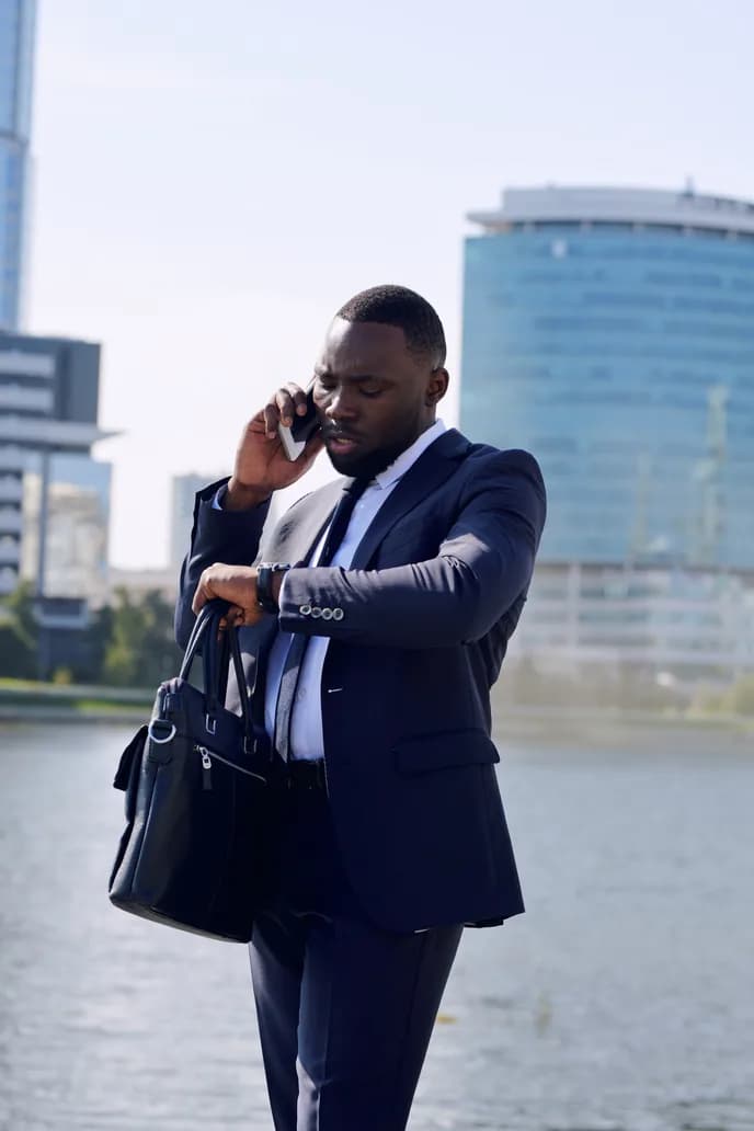 A travel agent taking a call outdoors with a client bag in hand