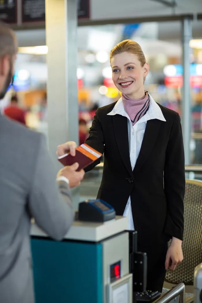 An airline agent handing a passport back to a passenger at check-in