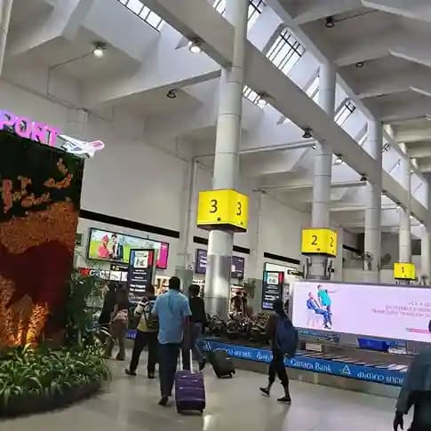 Travelers crossing an arrivals hall past numbered baggage claim belts