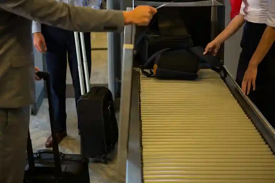 A traveler placing a bag onto a security screening conveyor
