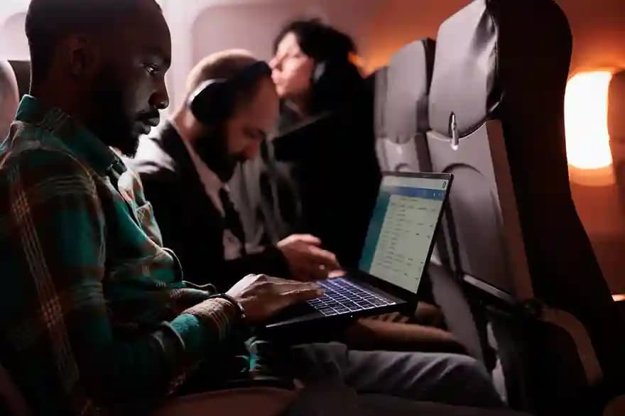 A traveler working on a laptop in an aircraft cabin