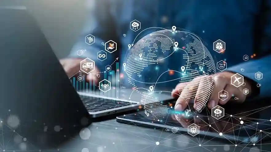 Hands on a laptop with a glowing globe and logistics icons overlaid