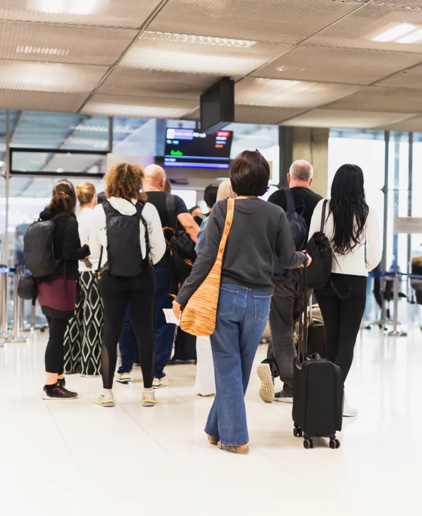 A traveler waiting in line with luggage at the airport