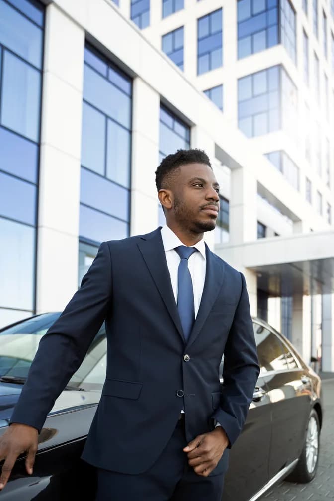 A chauffeur holding the rear door open for a passenger