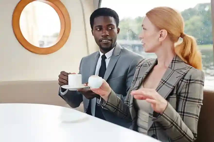 Two business travelers talking over coffee at a lounge table