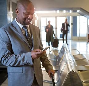 A business traveler checking a phone beside seating in a quiet terminal