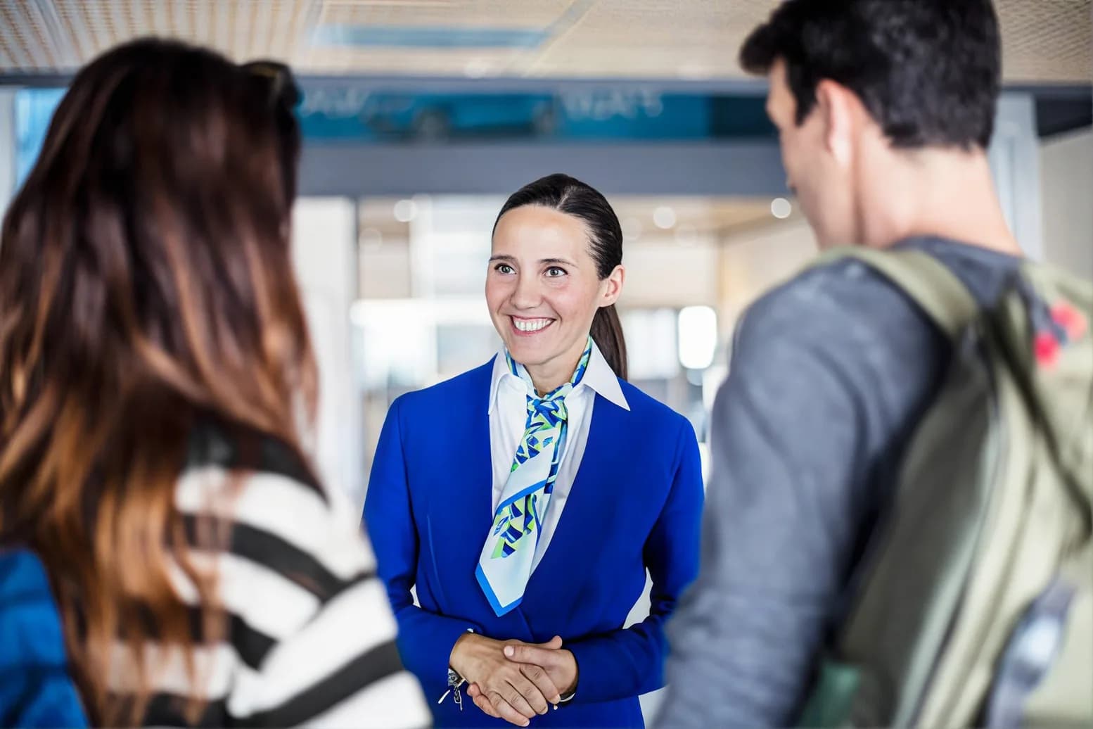 A uniformed greeter welcoming travelers inside an airport terminal