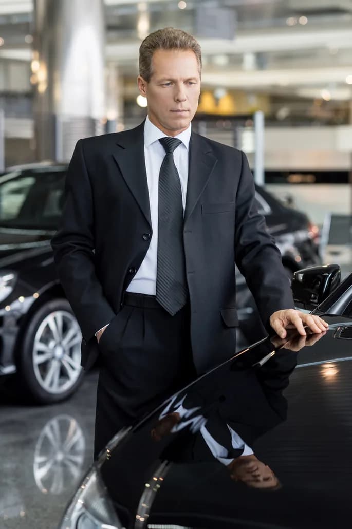 A traveler in a suit beside a waiting car after his connecting flight