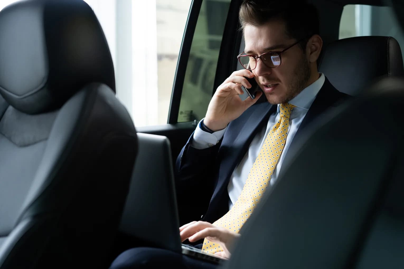 A traveler seated in the back of a chauffeured car