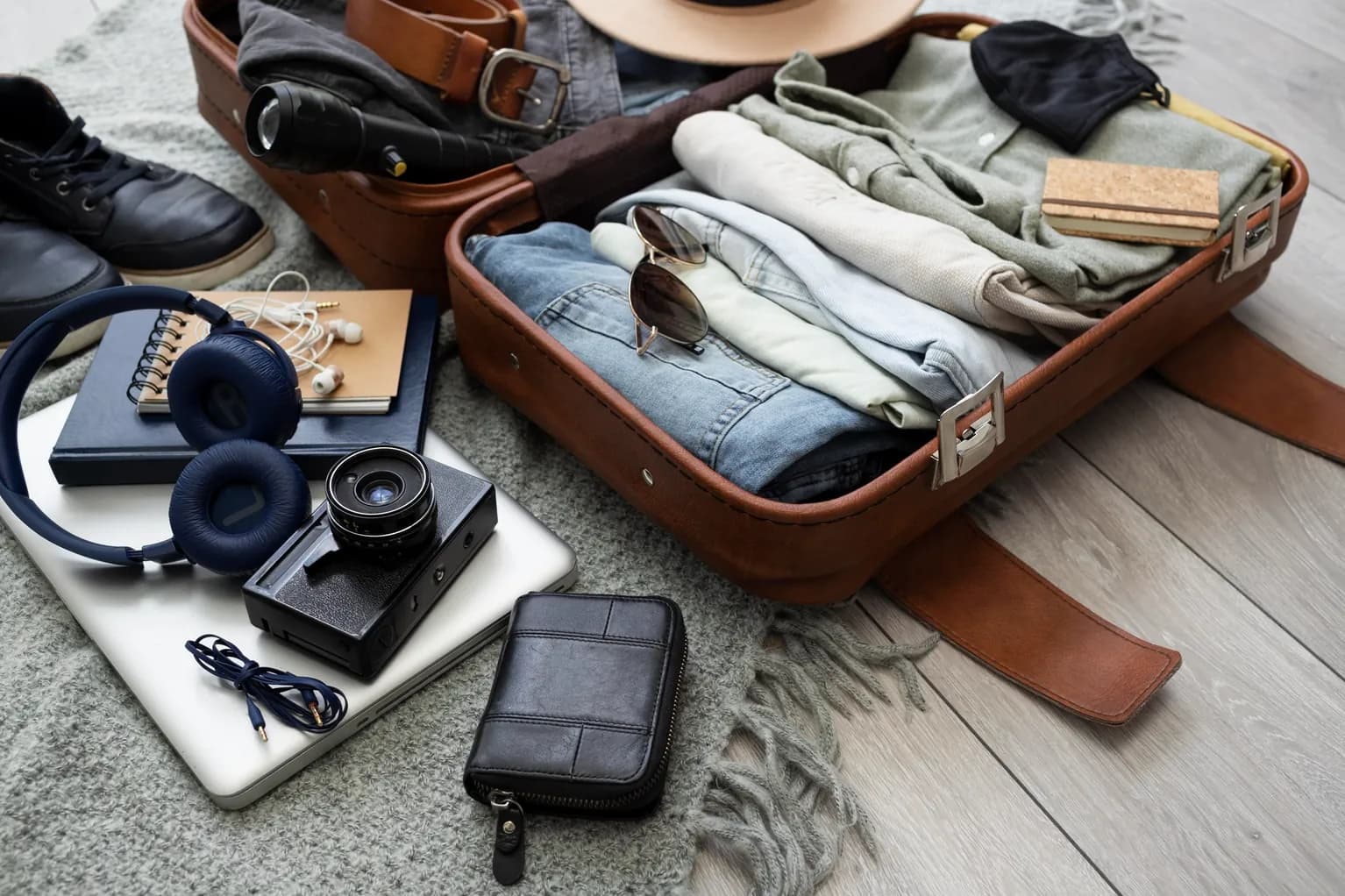 An open suitcase packed with folded clothes and travel documents
