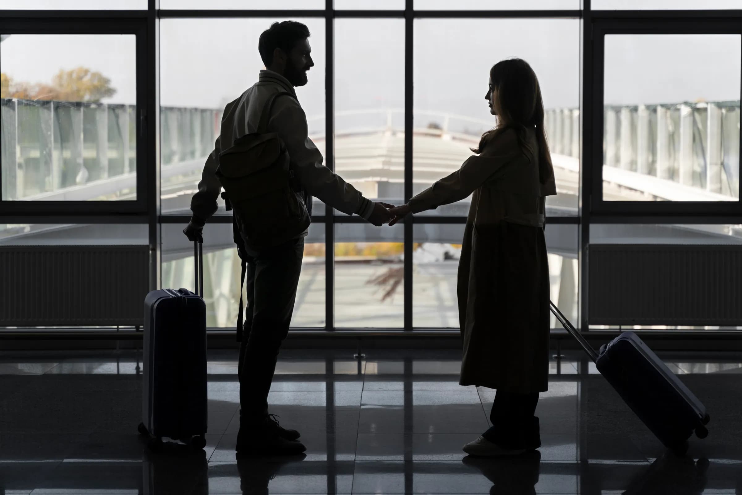 Two travelers meeting beside a terminal window between flights